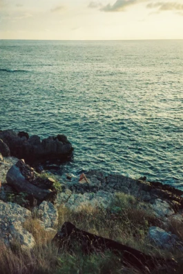 person relaxing on a cliff surrounded by the sea 